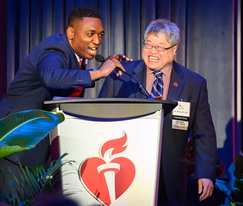 Photo of two men laughing behind the podium on stage.